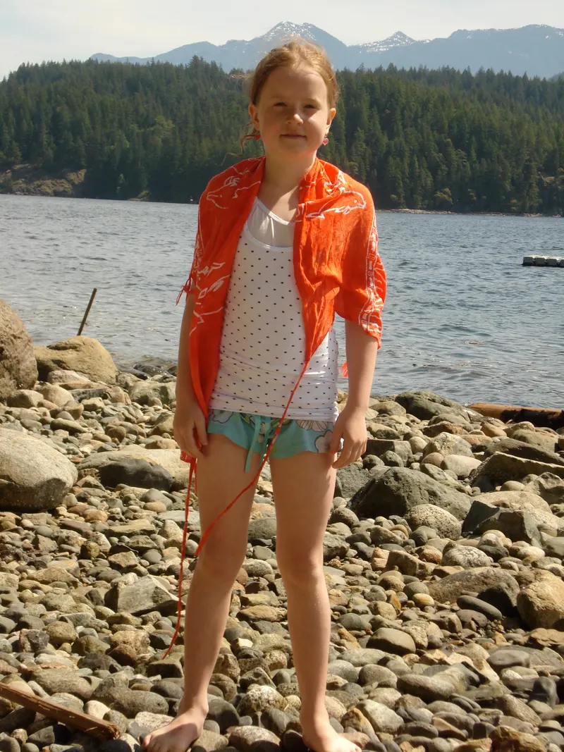 Sam as a child, standing on the rocky shore of Gambier Island