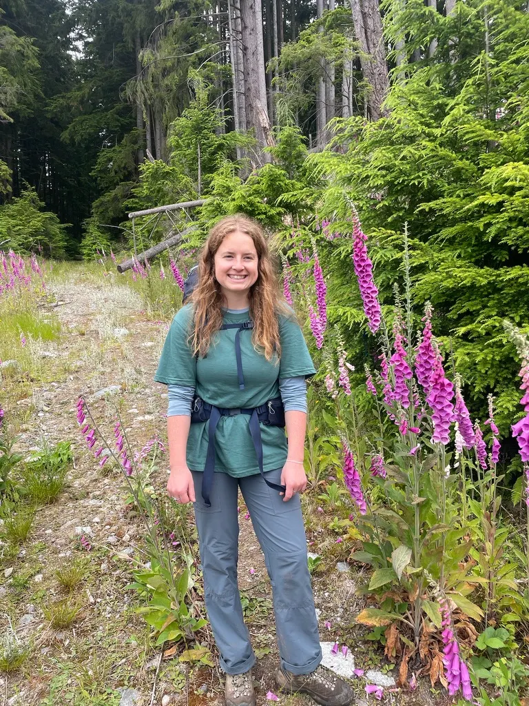 Sam hiking a forest trail on Gambier Island, foxgloves in bloom